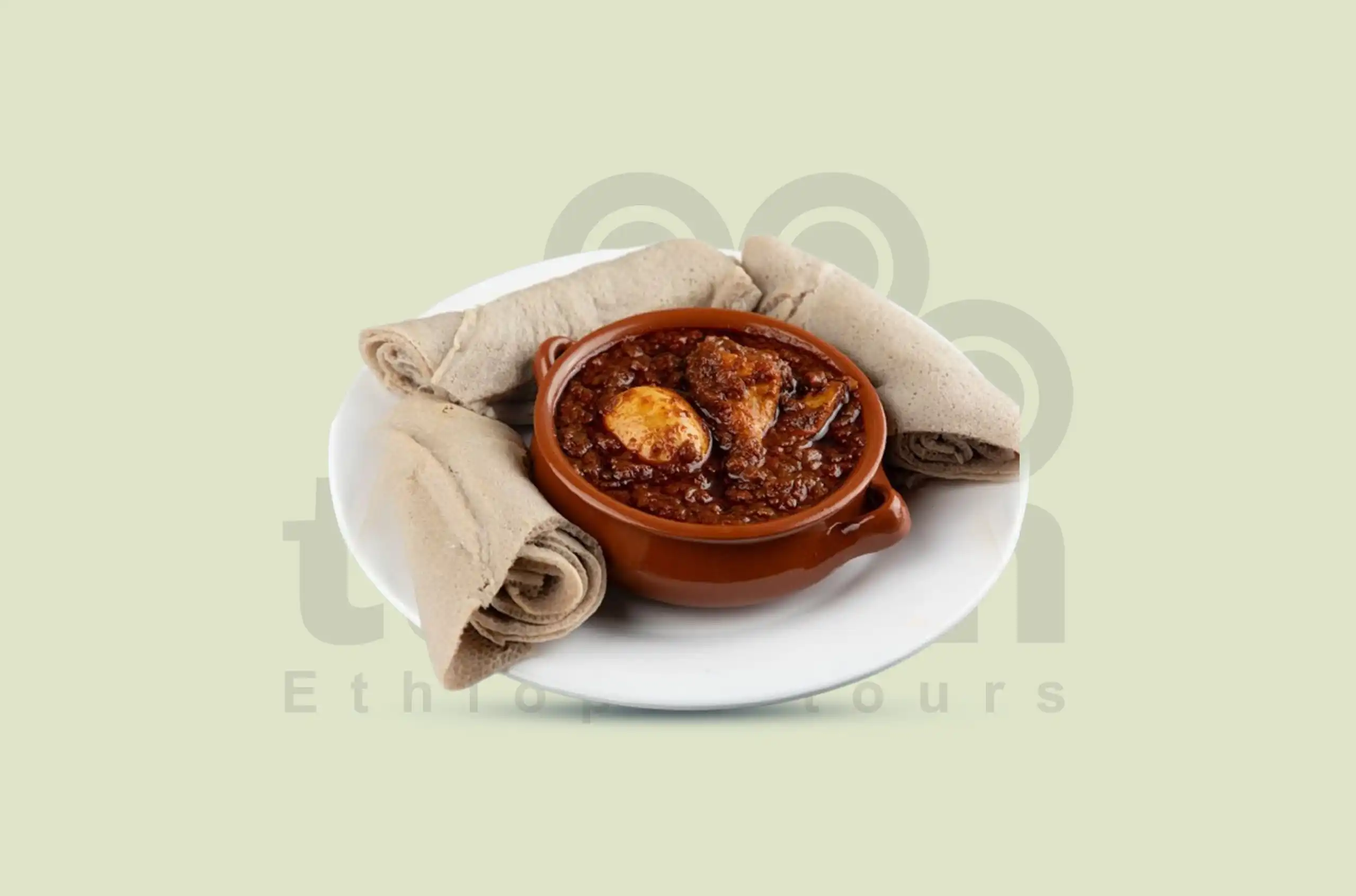 Tanian Ethiopia Tours presented a close-up of a plate of Doro Wot, an Ethiopian chicken stew. A chicken leg and a hard-boiled egg are visible in the stew, which has a deep reddish-brown color. Rolled pieces of injera bread are arranged around the stew.