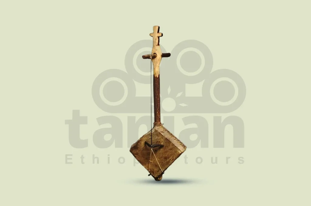 Photograph of a Masenqo, a single-stringed bowed lute from Ethiopia. The instrument is displayed against a light background with the "Tanian Ethiopia tours" logo subtly watermarked.