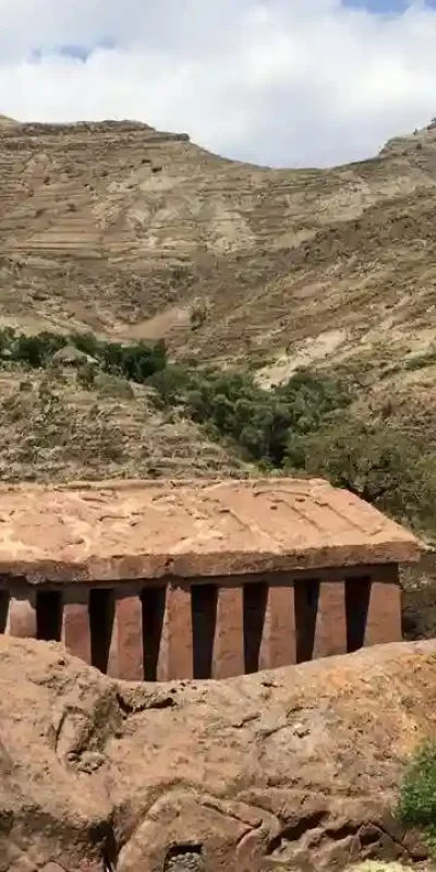 A top-down view of Genete Maryam Church in Lalibela, Ethiopia. The photograph shows the roof structure and layout of this rock-hewn church from an elevated perspective. The surrounding excavated courtyard and the natural rock formations around the church are also visible. This aerial or high-angle view emphasizes the monolithic nature of Genete Maryam and its integration into the landscape of Lalibela.