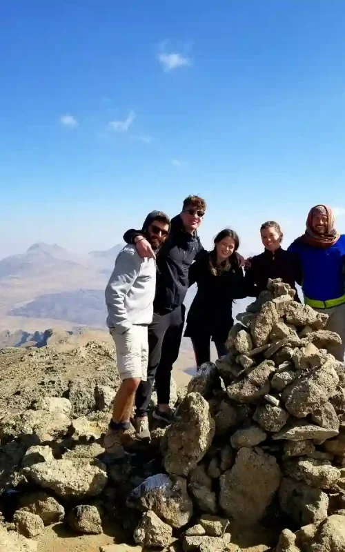 Tanian Ethiopia Tour clients celebrate their successful climb to Ras Dashen summit in Simien Mountains National Park, Ethiopia. The image shows a group of travelers enjoying the accomplishment of reaching the highest point in Ethiopia.